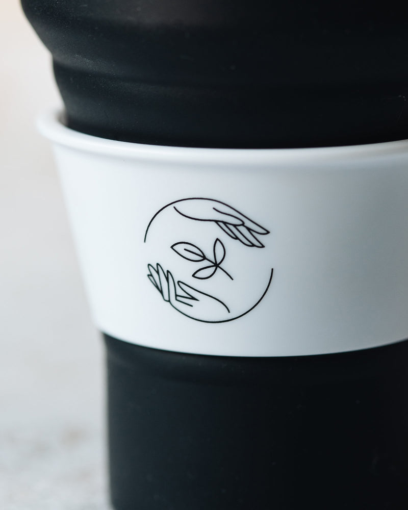 Close up of black Sasstainable logo on the white cup collar.