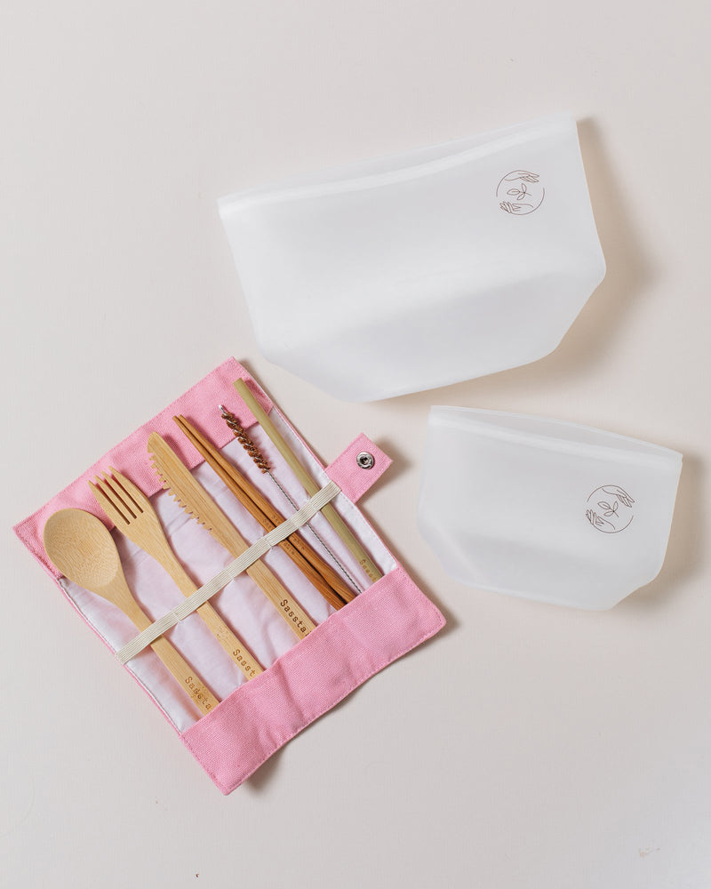 Large silicone pouch, small silicone pouch and open pink bamboo cutlery set on a plain white background.
