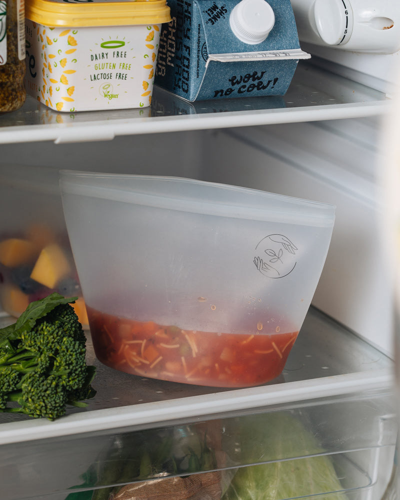 Medium pouch standing upright in a refrigerator containing a red noodle dish.