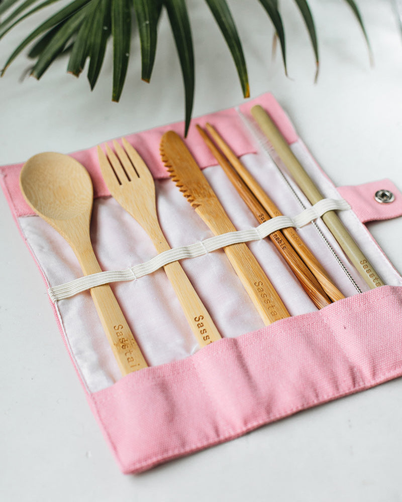 Bamboo spoon, fork, knife, chopsticks, straw cleaner and straw in a natural canvas case, on a white marble background.