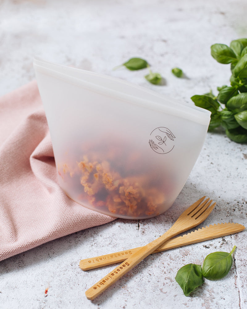 Large pouch sealed with rice dish inside, with bamboo knife and fork beside it.