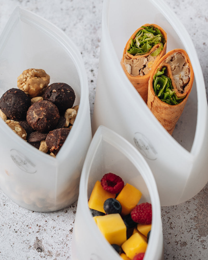 Three reusable pouches containing picnic food